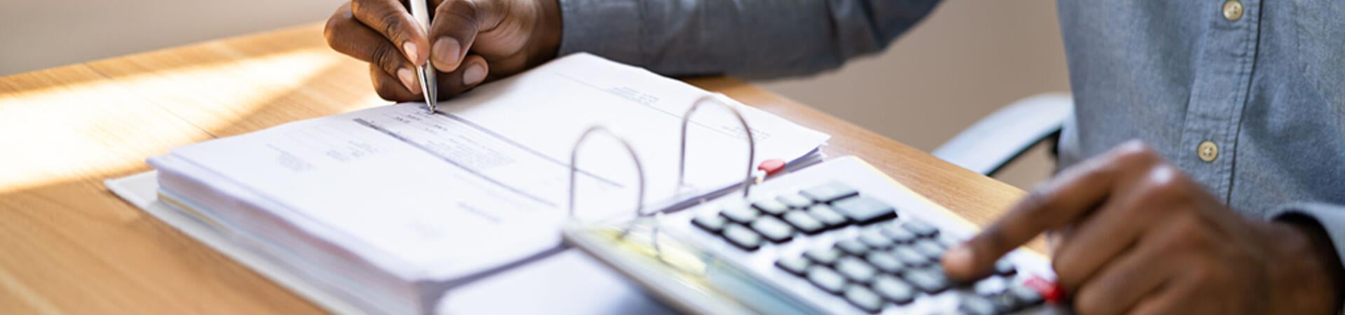 Person writing in a ledger and using a calculator